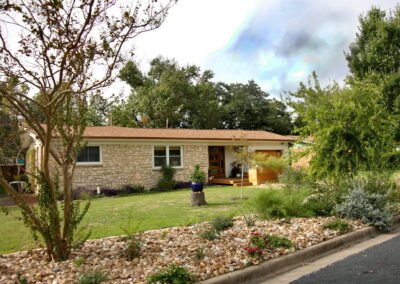 This is another view of the house from the left side. You can see closer views of the river rock beds with multi-colored lantana, native grasses, and an eight foot Crepe Myrtle Tree with red blossoms.