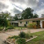 This image is a front view of 1403 Larkwood Dr. It shows the yard divided into rock beds with Texas Natives and areas with green grass.