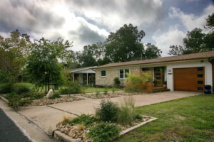 This image is a front view of 1403 Larkwood Dr. It shows the yard divided into rock beds with Texas Natives and areas with green grass.