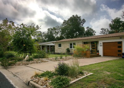 This image is a front view of 1403 Larkwood Dr. It shows the yard divided into rock beds with Texas Natives and areas with green grass.