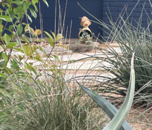 A little garden gnome framed by grasses and coral yuccas.