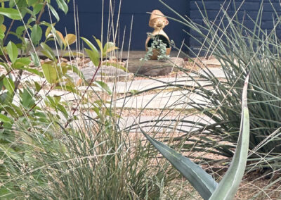 A little garden gnome framed by grasses and coral yuccas.