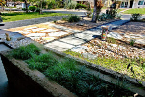 An image of the vintage brick planter box attached to the house which contains Various shade loving grasses.