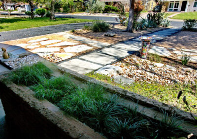 An image of the vintage brick planter box attached to the house which contains Various shade loving grasses.