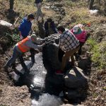 Chad, Roman, unknown, Katie, and Dan lifting a 4 ft tractor tire out of the mucky bottom of the creek.