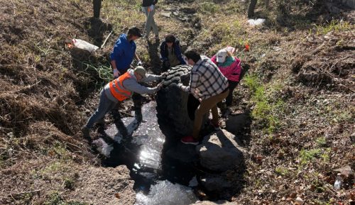 Chad, Roman, unknown, Katie, and Dan lifting a 4 ft tractor tire out of the mucky bottom of the creek.
