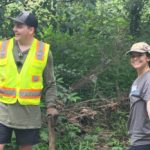 Evan in a safety vest and Hanna picking up trash