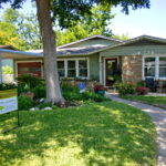 Another view of the front of the house with a curved walkway leading to the front door and anchored by beds of flowers on each side.