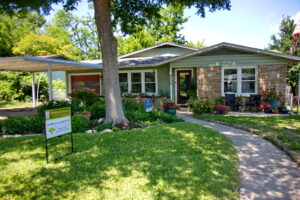Another view of the front of the house with a curved walkway leading to the front door and anchored by beds of flowers on each side.