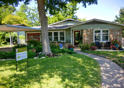 Another view of the front of the house with a curved walkway leading to the front door and anchored by beds of flowers on each side.