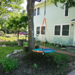 A side view of the house with a circle swing hanging from a pecan tree.