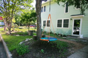 A side view of the house with a circle swing hanging from a pecan tree.