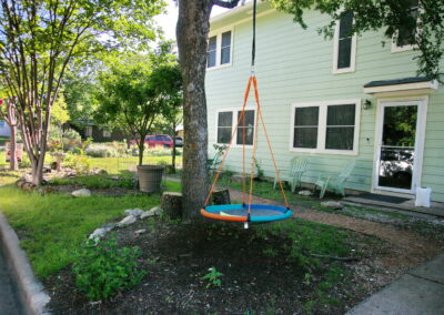 A side view of the house with a circle swing hanging from a pecan tree.