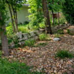 A river rock pathway leads to another bed of pollinators.