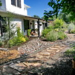 Another view of the stone walkway which leads to the front porch. Along side you'll find red salvia, a trellis with a climbing rose bush, and various flowering shrubs.