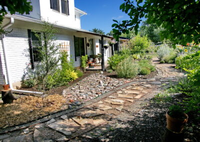 Another view of the stone walkway which leads to the front porch. Along side you'll find red salvia, a trellis with a climbing rose bush, and various flowering shrubs.
