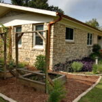 An image depicting the carved out beds of container vegetable gardens. The beds are covered with a red cedar mulch and contain rectangle wood container boxes for fresh from the garden vegetables.