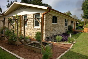 An image depicting the carved out beds of container vegetable gardens. The beds are covered with a red cedar mulch and contain rectangle wood container boxes for fresh from the garden vegetables.
