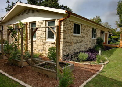 An image depicting the carved out beds of container vegetable gardens. The beds are covered with a red cedar mulch and contain rectangle wood container boxes for fresh from the garden vegetables.