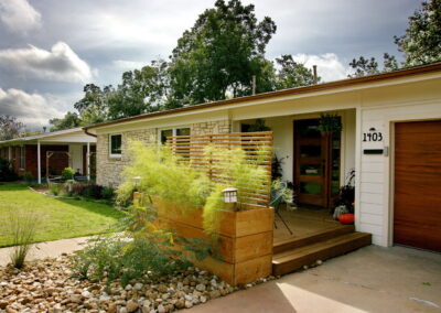 This is a view of the wood deck front porch which is lined by a tall wood container box filed with feathery bamboo muhly.