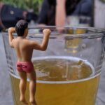 Plastic figurine hanging from the edge of a glass of beer