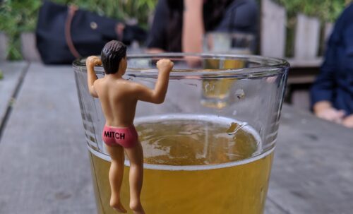 Plastic figurine hanging from the edge of a glass of beer