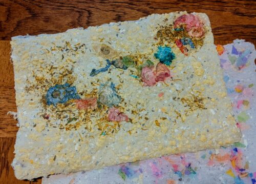 Colorful paper with embedded flowers and construction paper made by members of the WPNA at the Austin Creative Reuse Center
